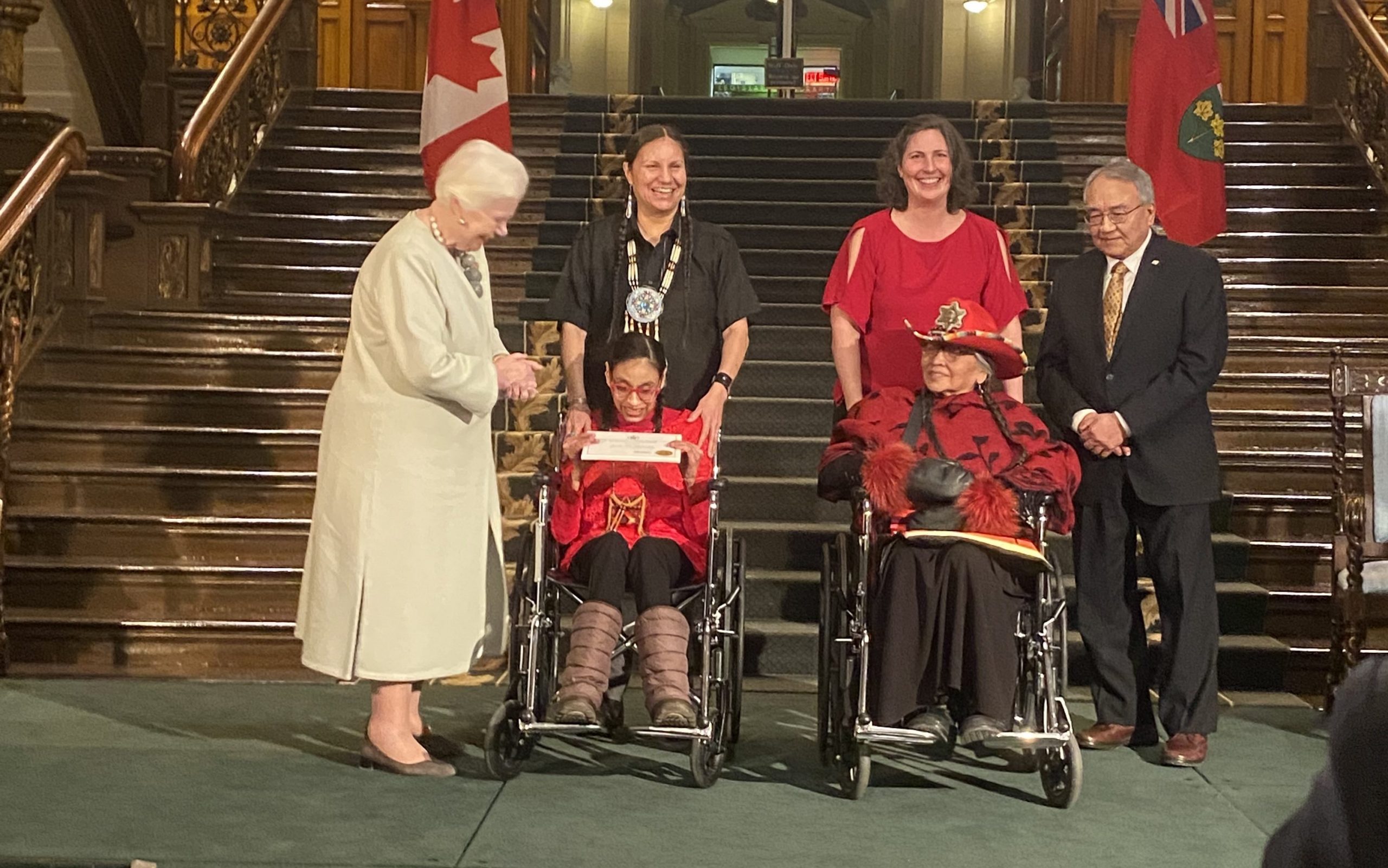 A photo of Lieutenant Governor of Ontario Elizabeth Dowdeswell, Dolleen Tisawii'ashii Manning, Sky Stonefish, Evadne Kelly, Mona Stonefish, and Judge Albert Wong on stage at the Ontario Heritage Award ceremony. 